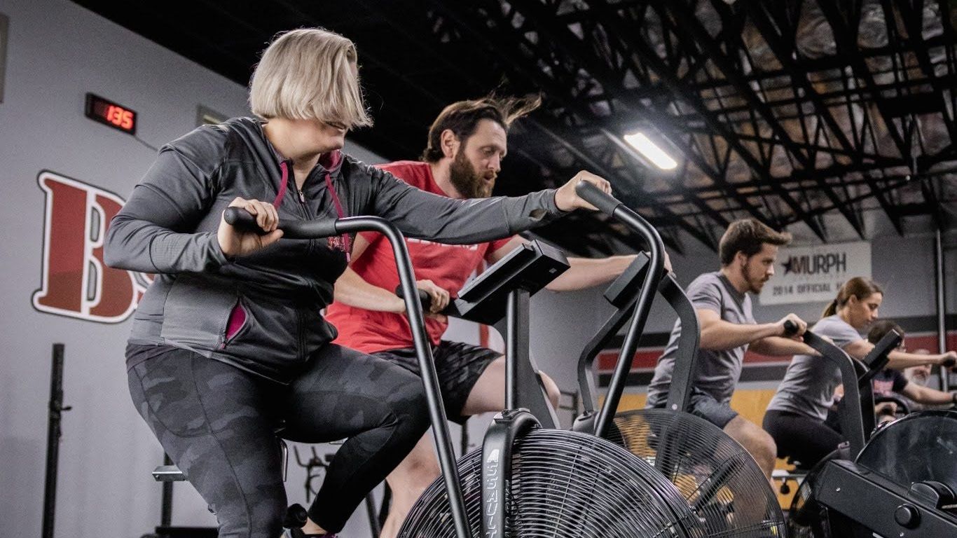 A group of people are riding exercise bikes in a gym.