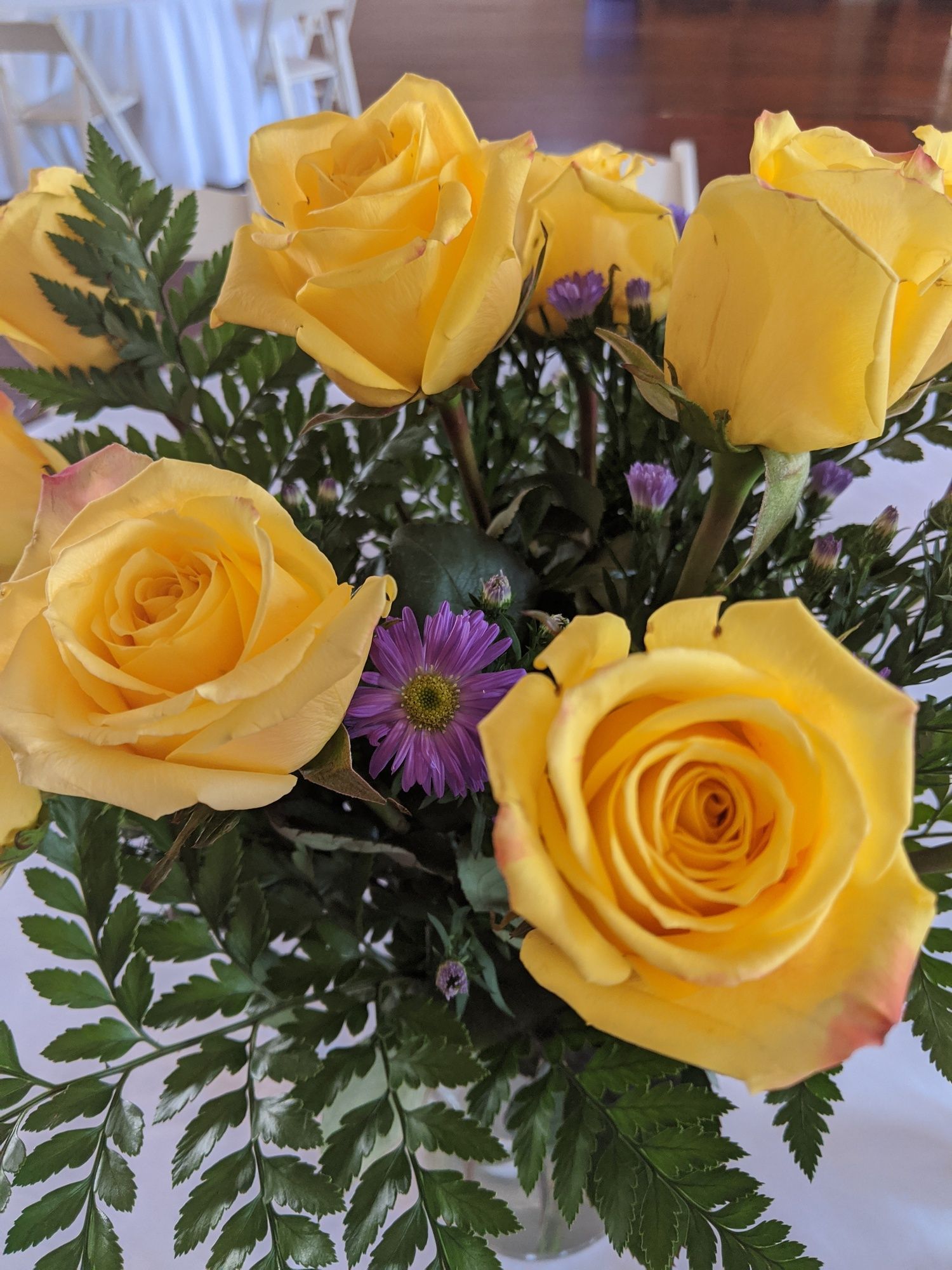 A vase filled with yellow roses and purple flowers