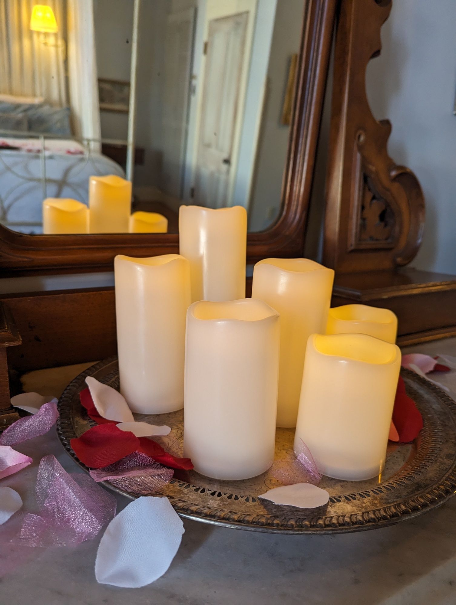 A tray of candles and rose petals on a table in front of a mirror