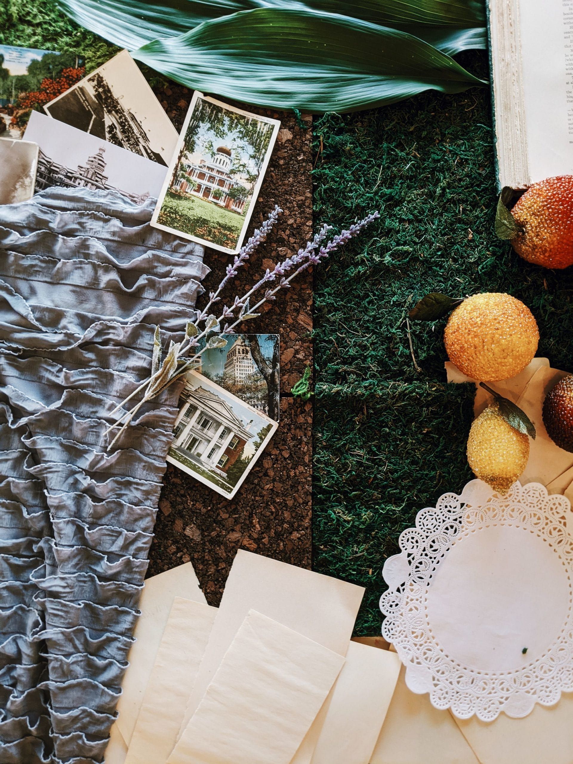 A collage of papers , fruits , flowers and leaves on a table.