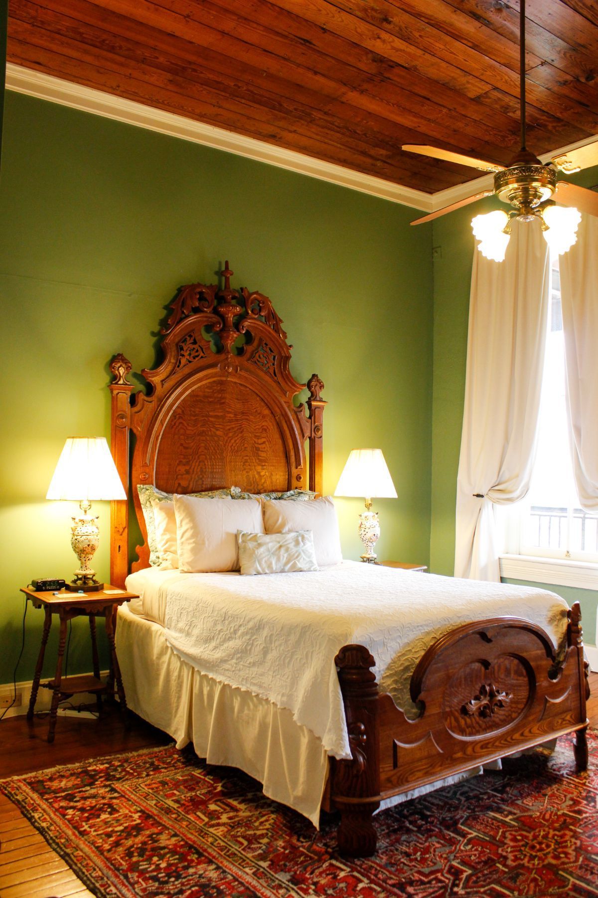 A bedroom with a bed , lamps , and a ceiling fan.