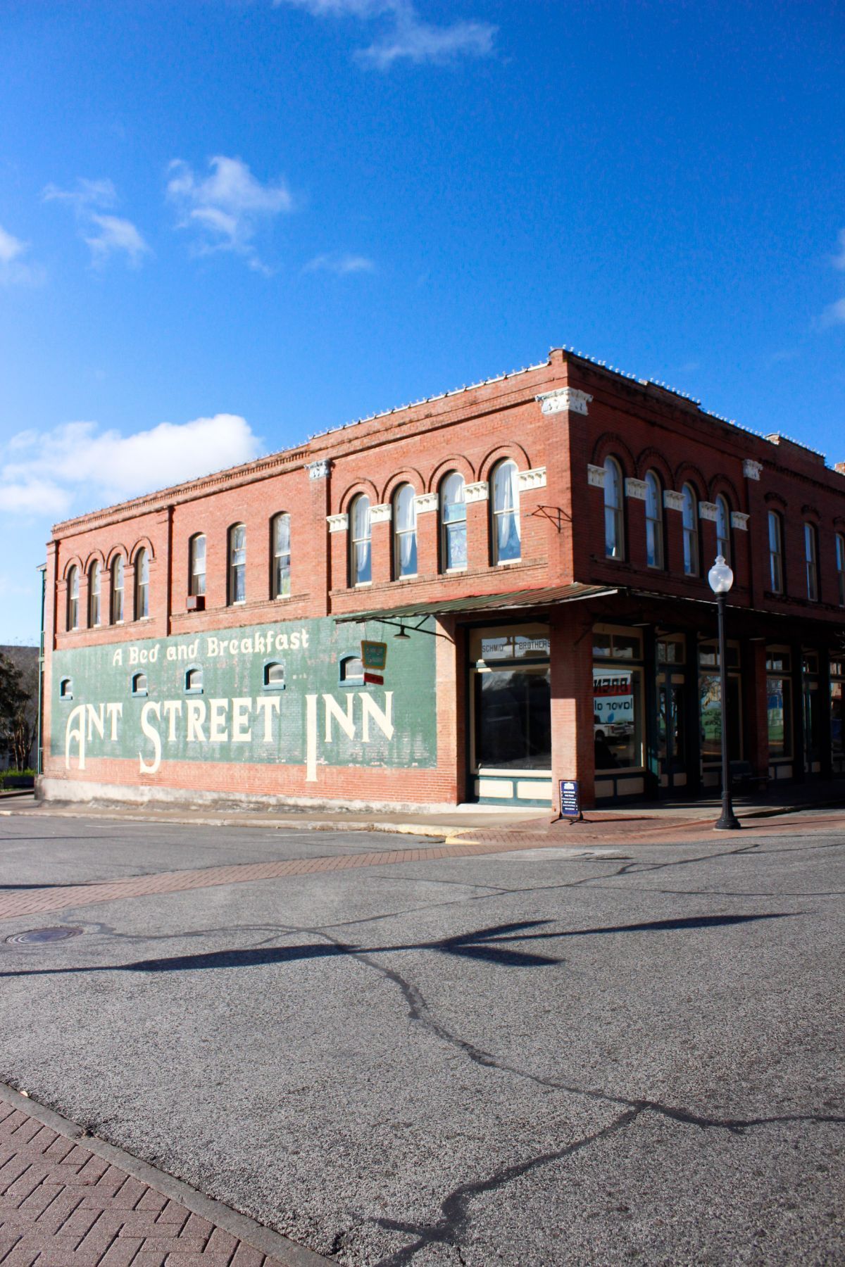A large brick building with a green sign on the side that says ant street inn.