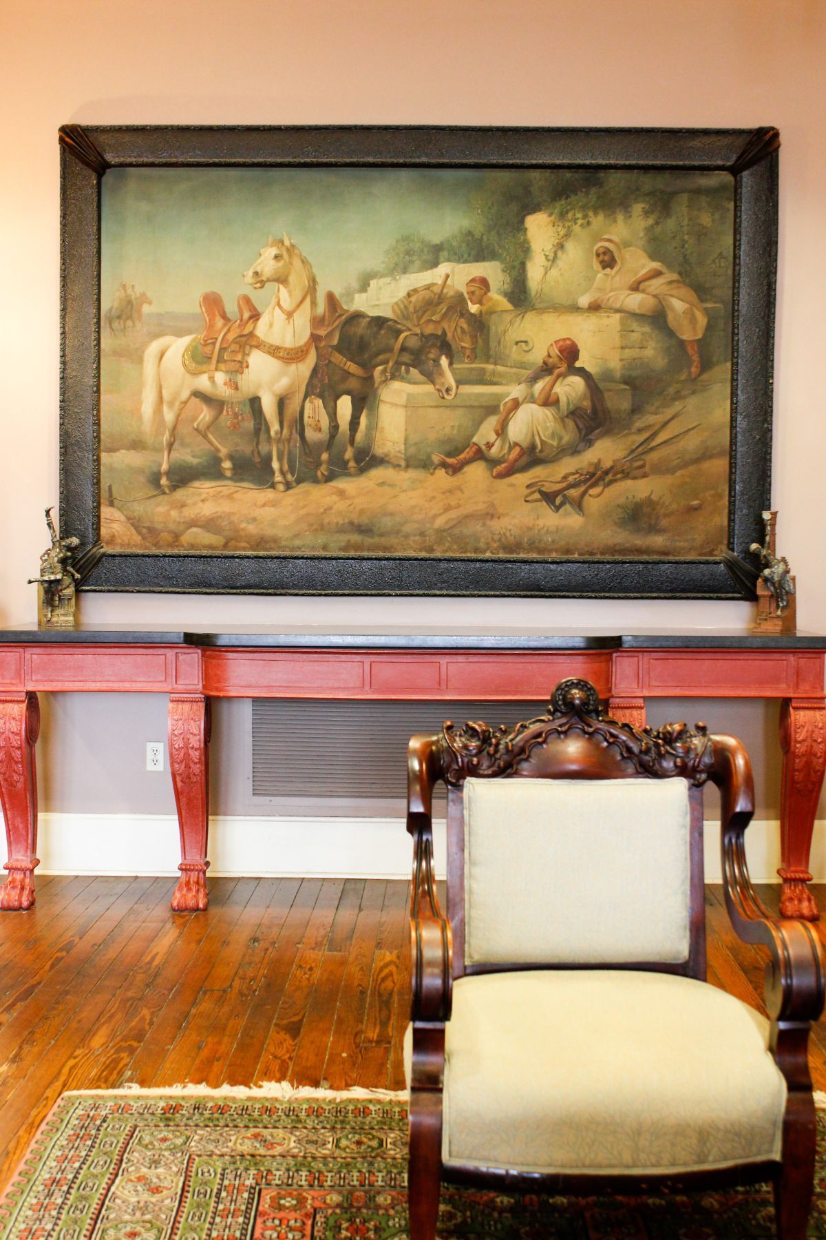 There is a large painting on the wall above the chair.