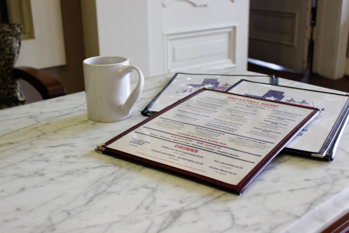 A coffee mug sits on a table next to a menu