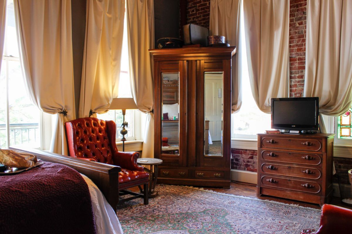 A bedroom with a bed , chair , dresser and television.