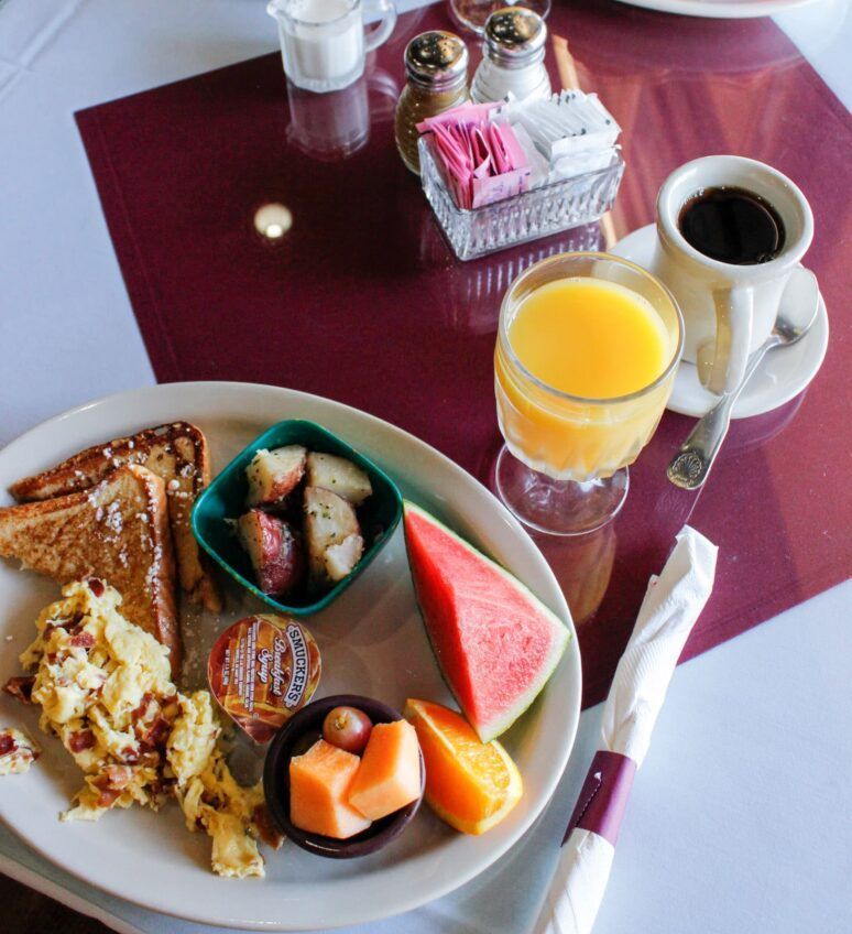 A plate of food on a table with a cup of coffee and a glass of orange juice