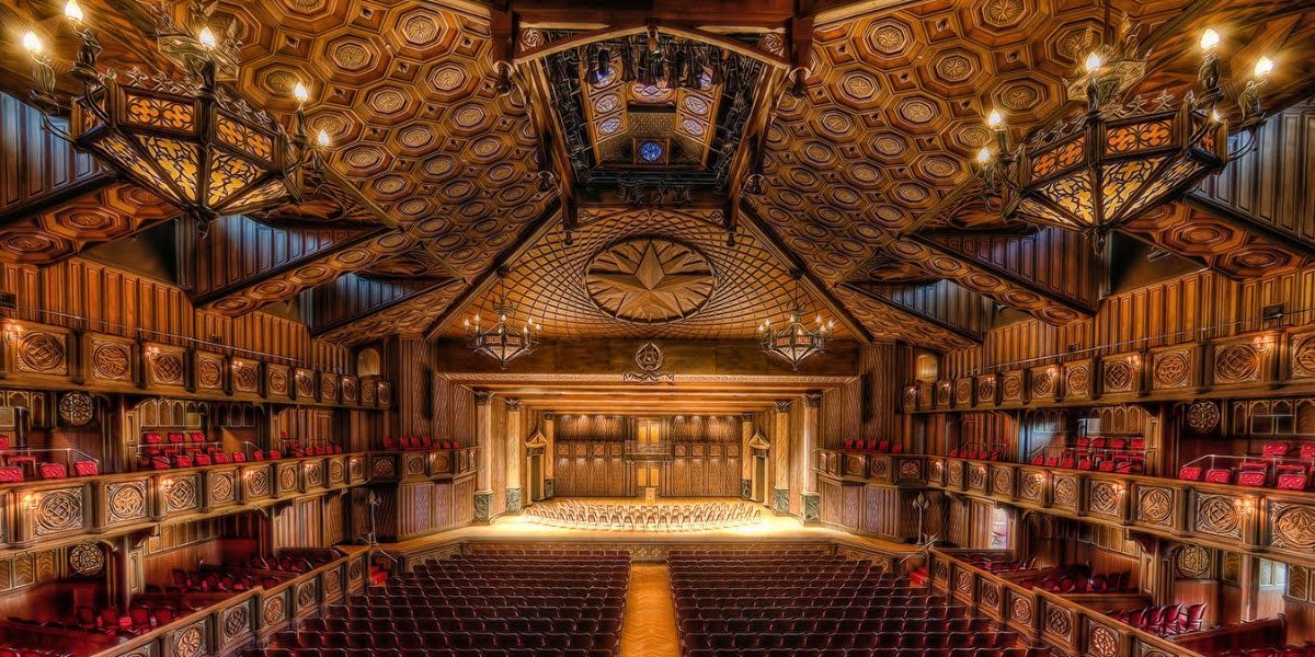 A large auditorium filled with rows of red seats and a stage.