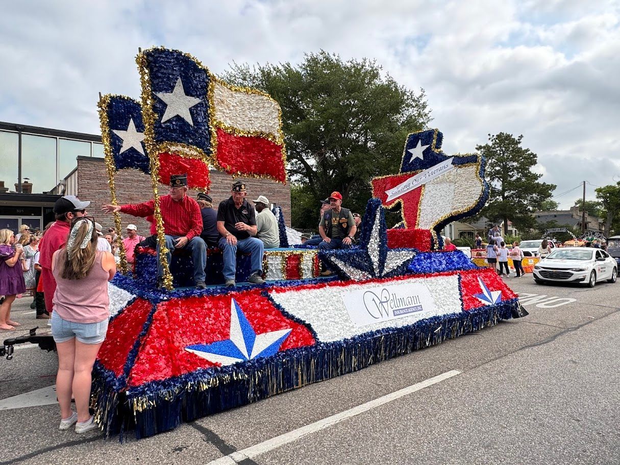 Texas-themed parade float decorated in red, white, and blue, with people riding on it.