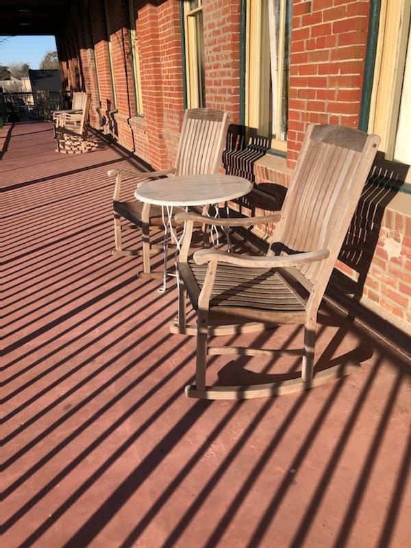 There are two rocking chairs and a table on the porch.