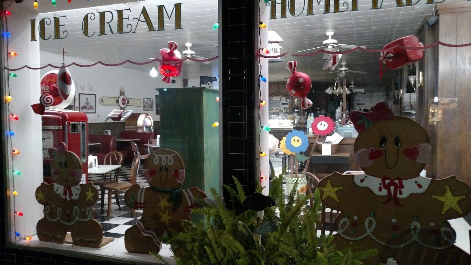 Christmas-decorated ice cream shop window with gingerbread figures and festive lights.