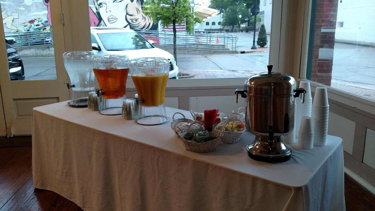 A table with a white tablecloth and drink dispensers on it.