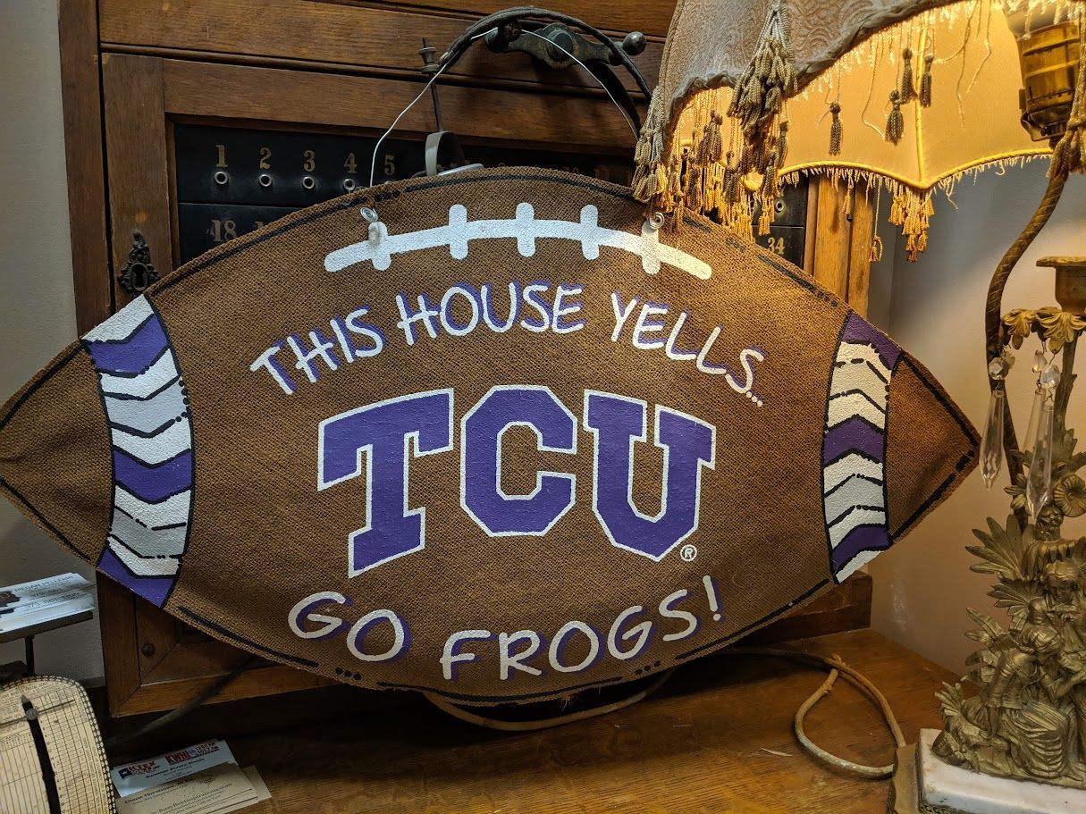 A football shaped sign that says this house yells tcu go frogs