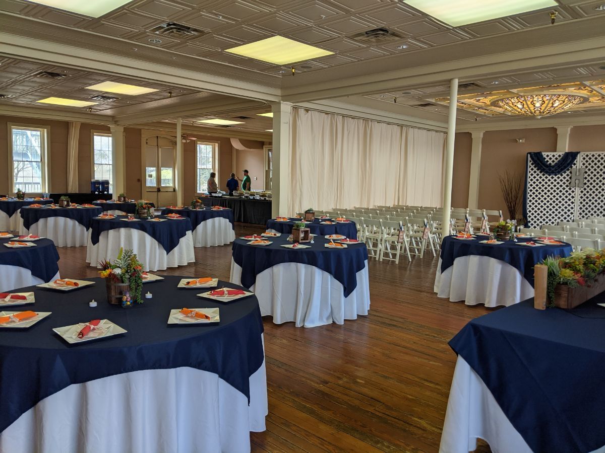 A large room with tables and chairs set up for a wedding reception.