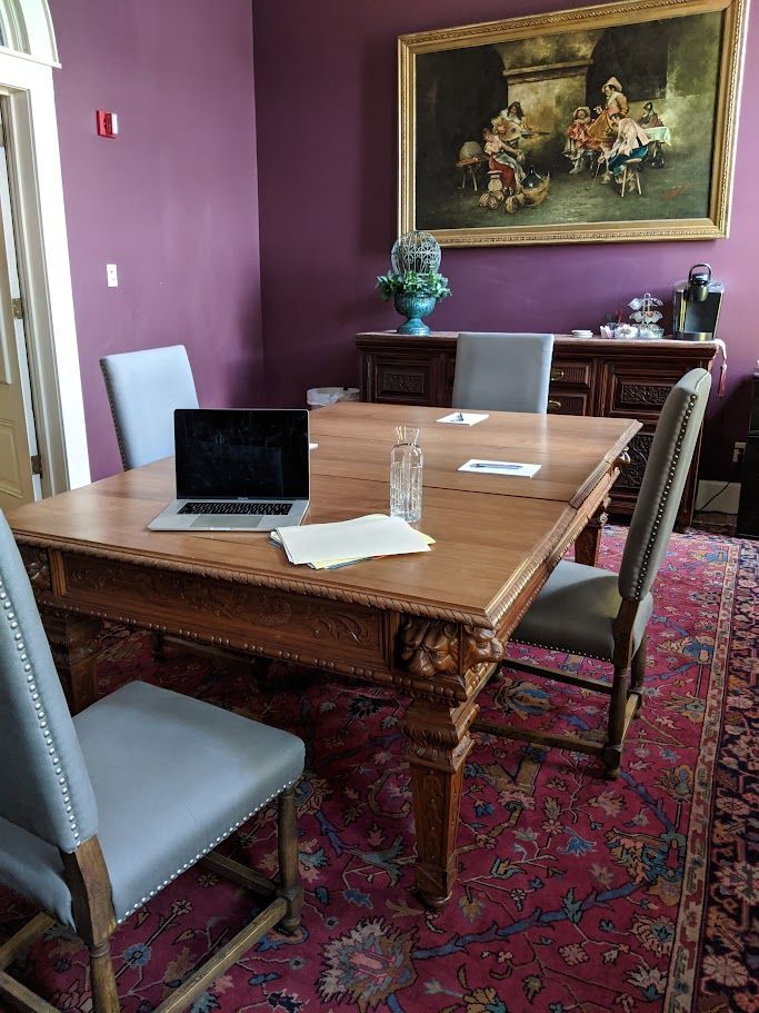 A conference room with a wooden table and chairs and a laptop on it.