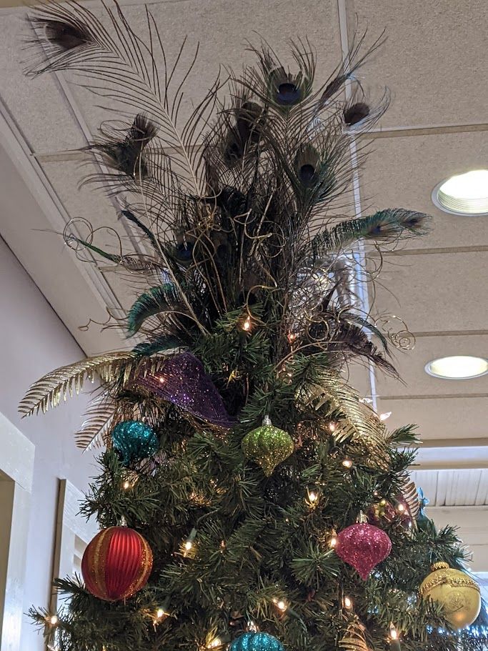Christmas tree decorated with peacock feathers and colorful ornaments.