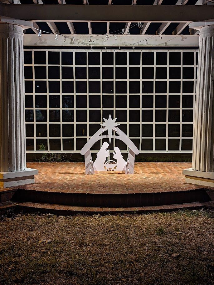 Nativity scene cutout under white pergola at night, with classic columns on either side.