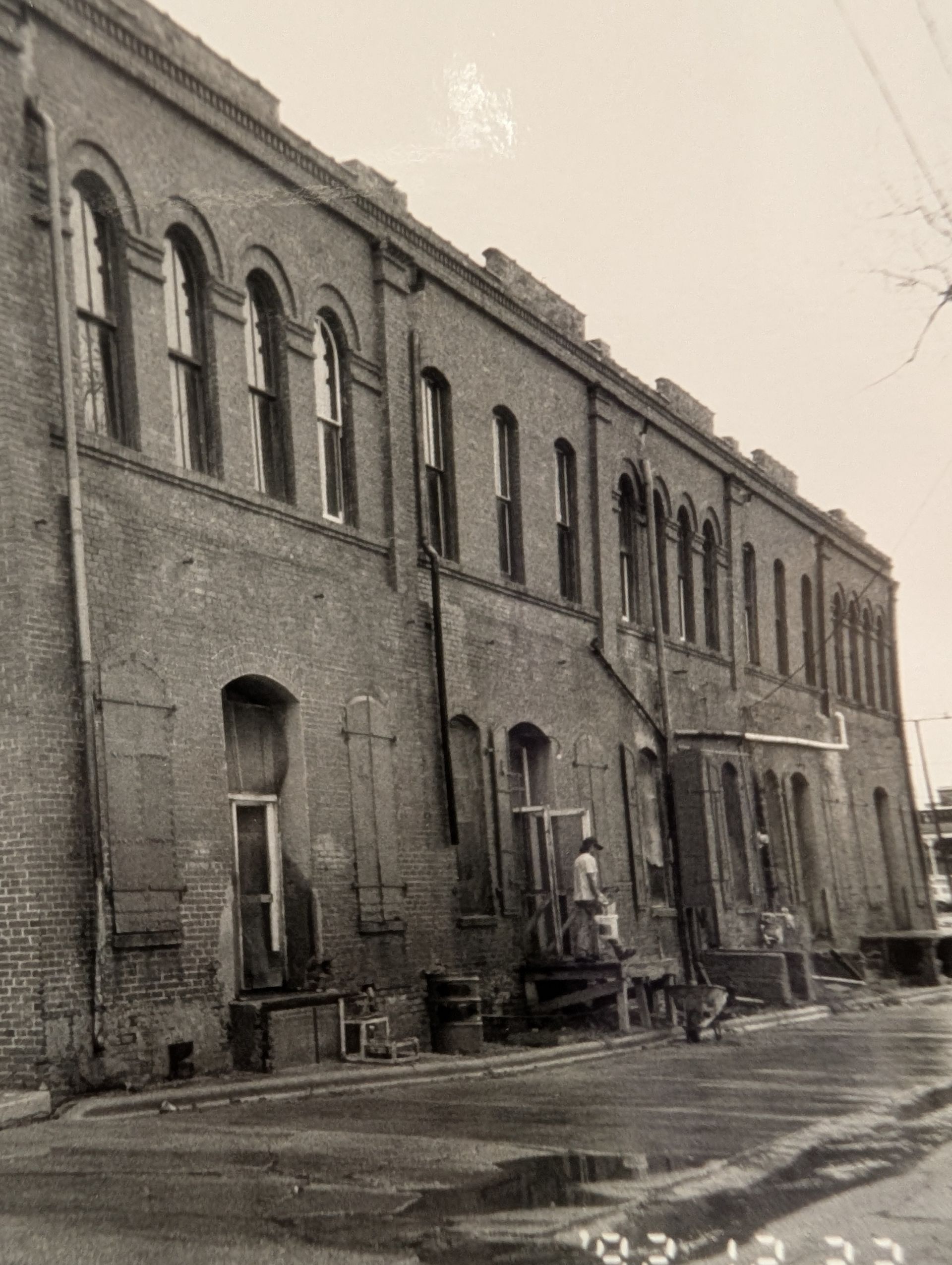 Brick building with arched windows, in black and white, outdoors.