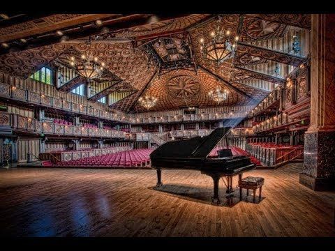 A grand piano is sitting in the middle of the empty round top festival institute auditorium