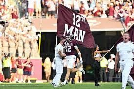 A football player is running with a flag that says 12th man on it.