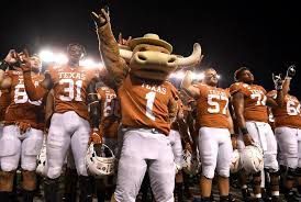 A group of football players are standing on a field with a mascot.