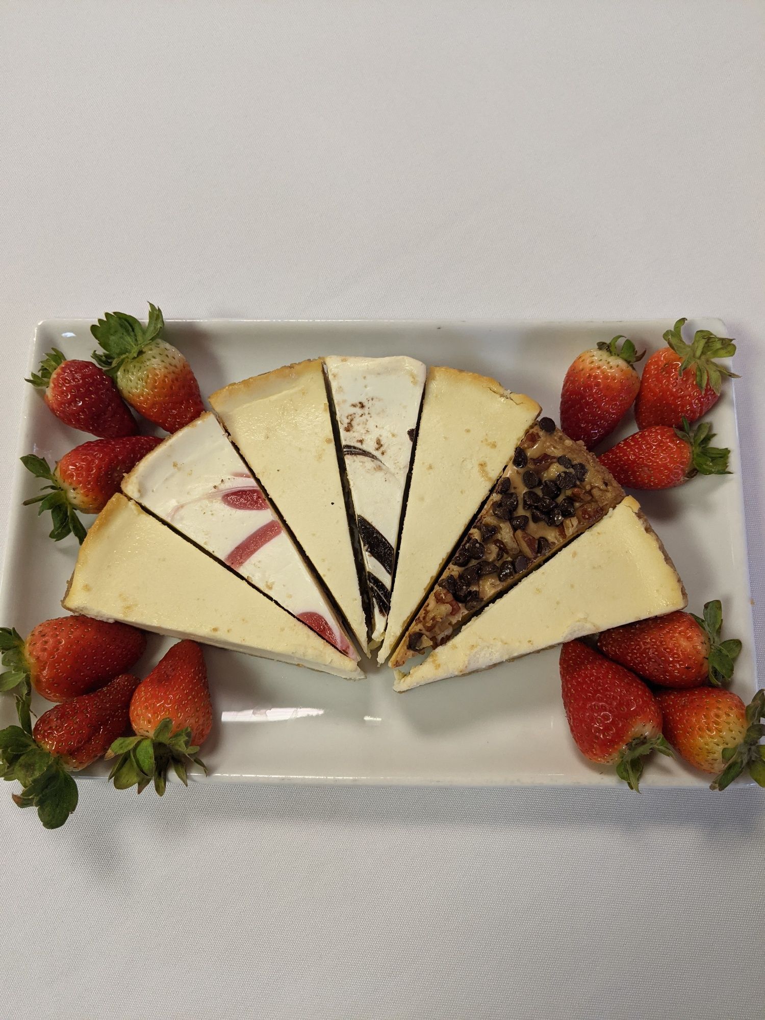 A white plate topped with slices of cheesecake and strawberries