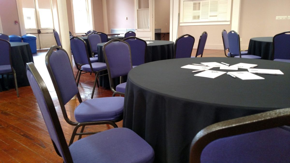 A room with tables and chairs and a black table cloth