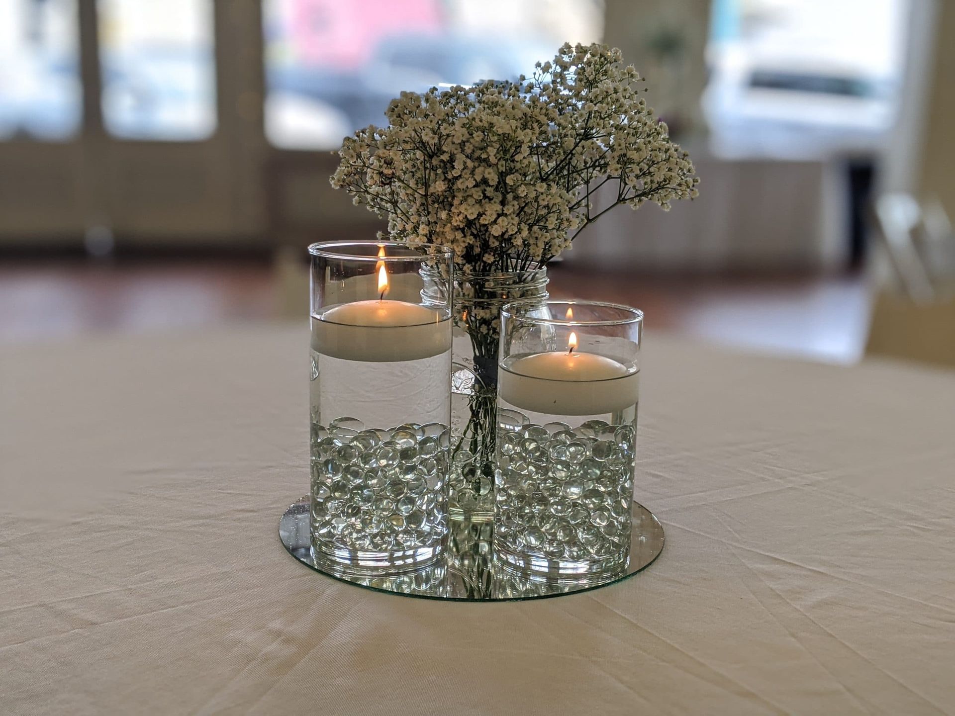 A vase filled with baby 's breath and two candles on a table.