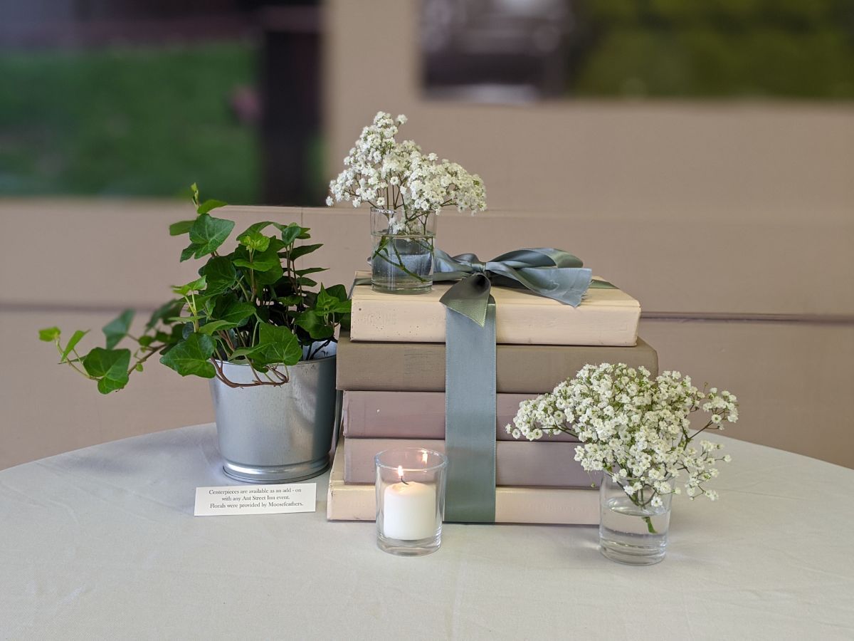 A stack of books with flowers and a candle on a table.