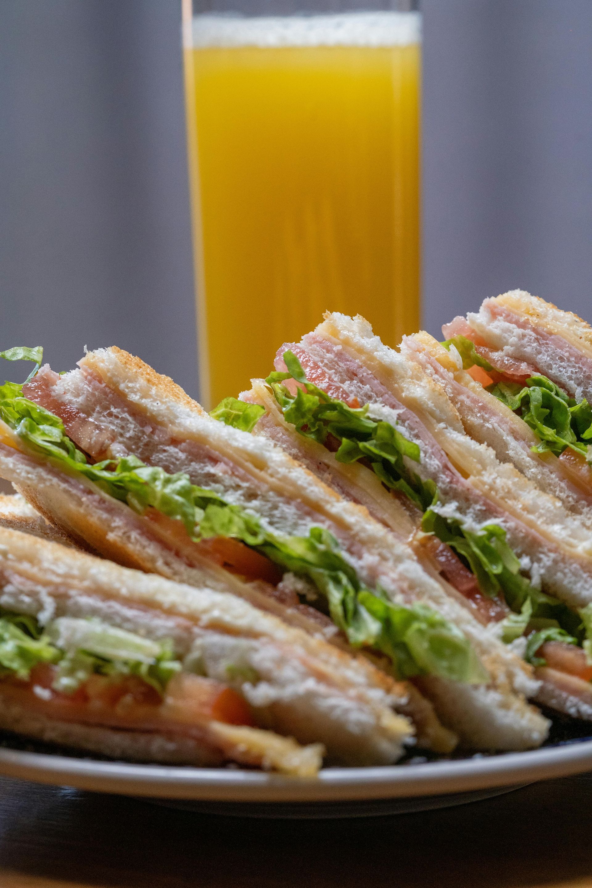 A plate of sandwiches and a glass of orange juice on a table.