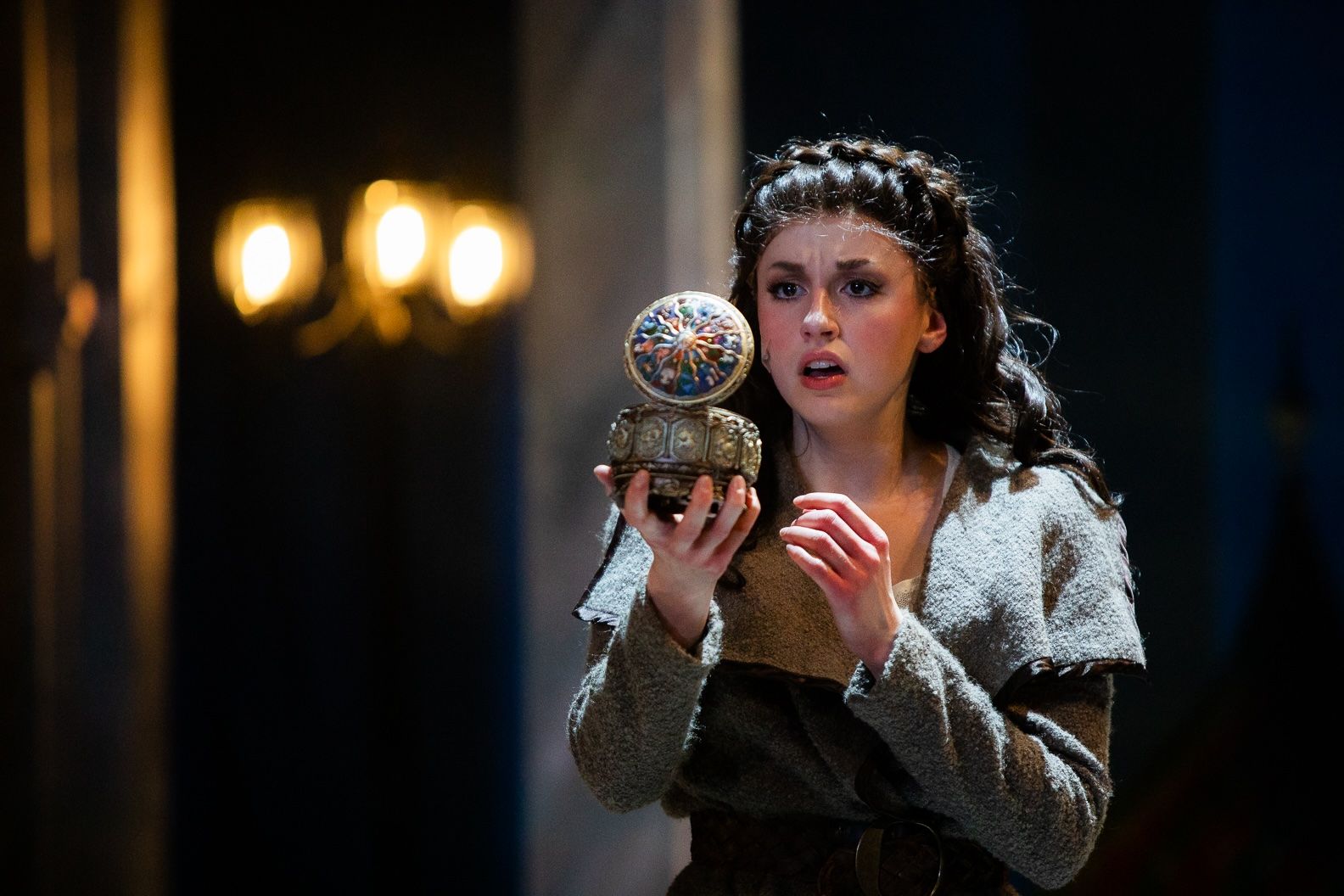 A woman is holding a ball in her hands on a stage.