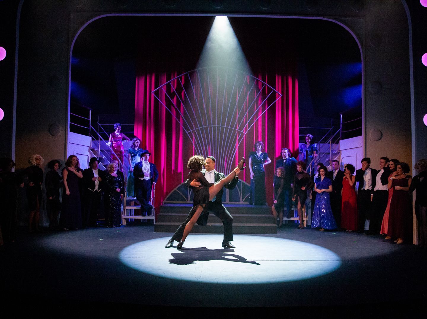 A man and woman are dancing on a stage in front of a crowd.