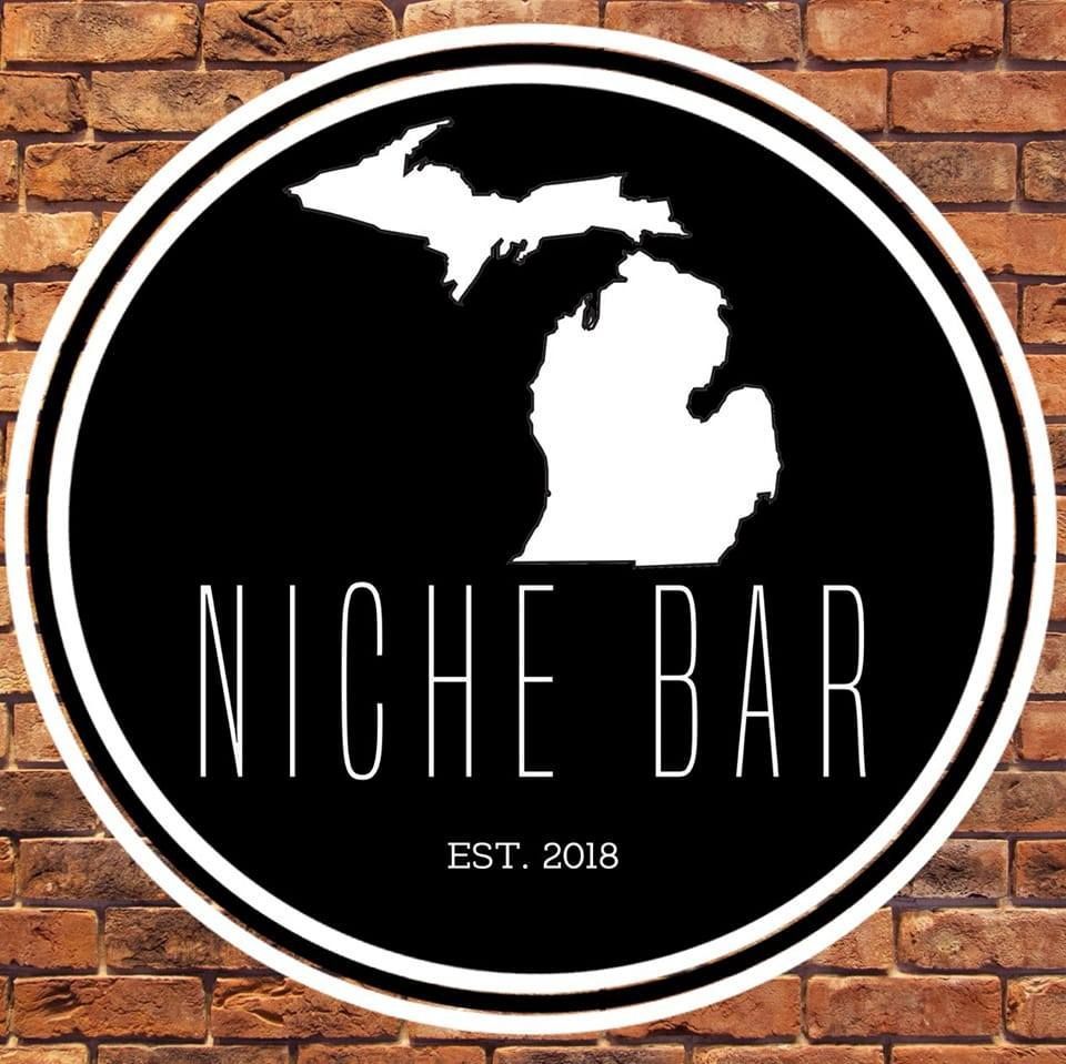 A logo for niche bar is on a brick wall