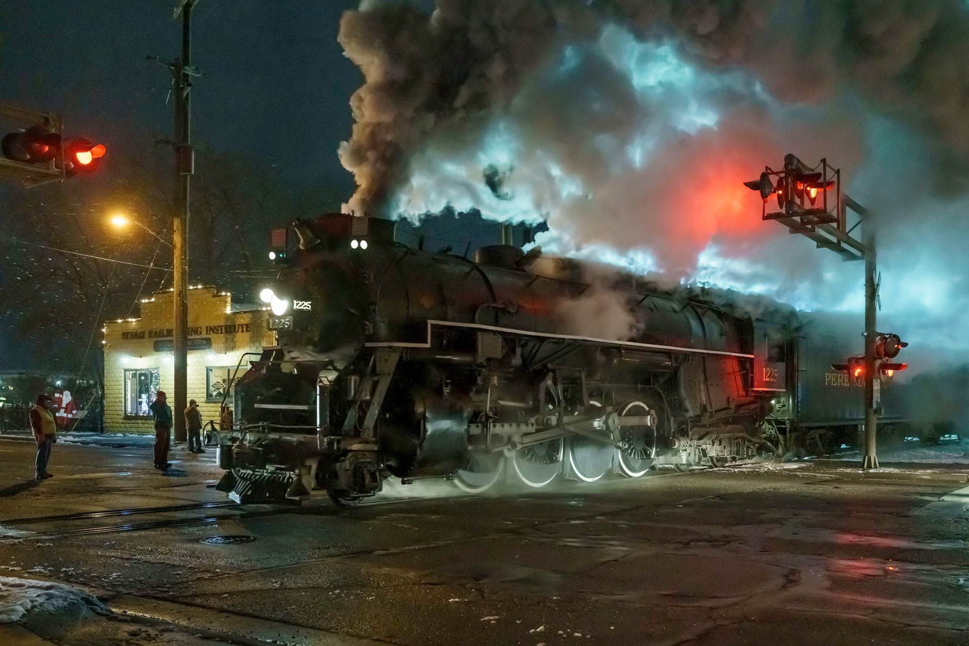 a steam train going through an intersection at night.