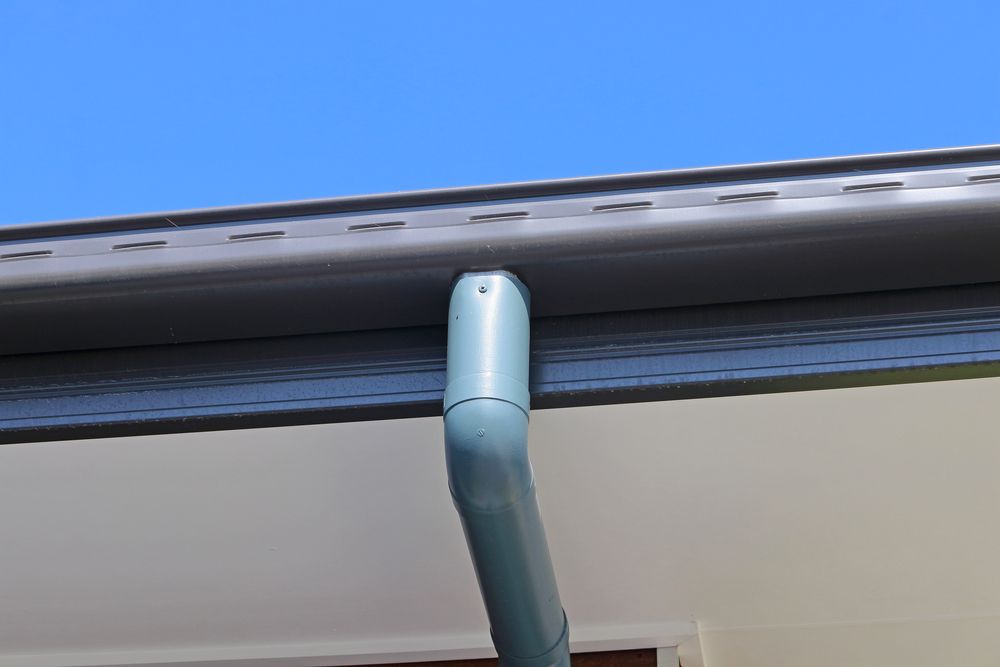 Grey Rain Gutter and Downspout on a White Building — GCX Roofing In Ashmore, QLD