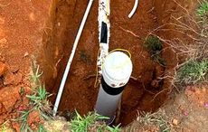 A white pipe is sticking out of a hole in the ground.