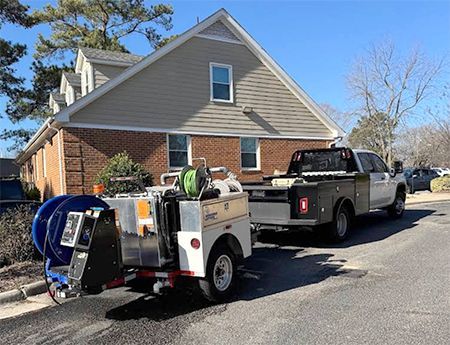 Two trucks and a trailer are parked in front of a house.