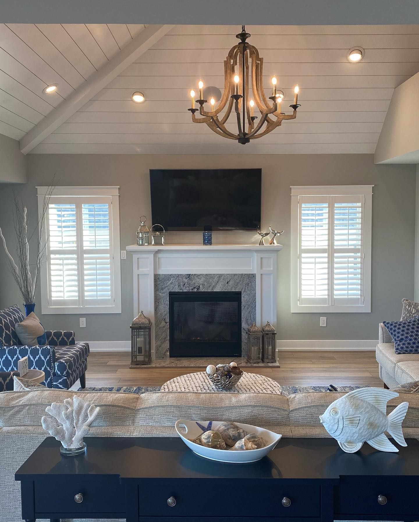 living room with fireplace, TV, chandelier, shutters, and nautical decor renovated by j.k. construction llc in avalon, new jersey