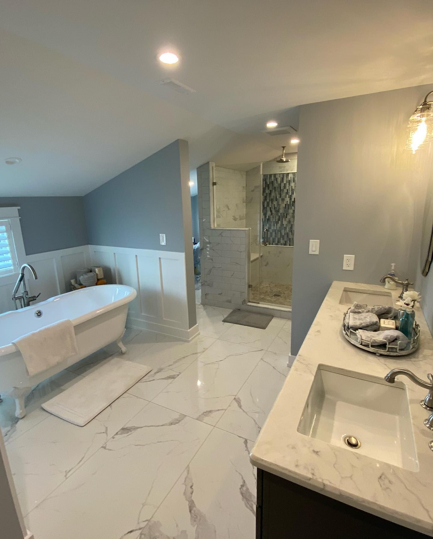 elegant bathroom with a white clawfoot tub, marble-look tile, and a glass shower renovated by j.k. construction llc in stone harbor, new jersey
