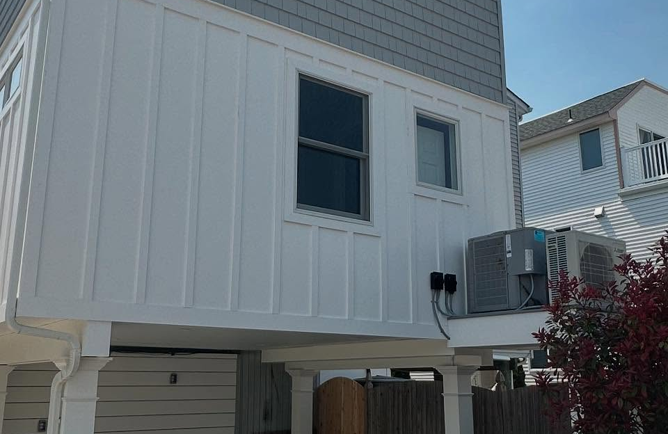 newly built addition on a white house exterior with vertical siding and air conditioning unit in strathmere, new jersey by j.k. construction llc