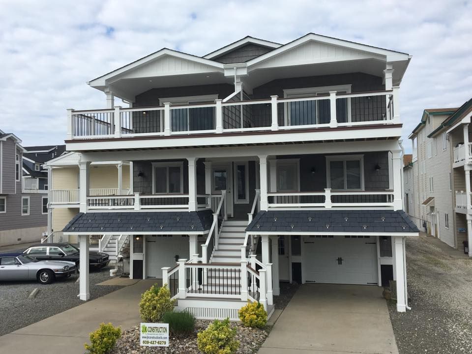 a exterior renovated, two-story gray beach house with balconies, steps, and white garage doors in ocean city, new jersey done by j.k. construction llc