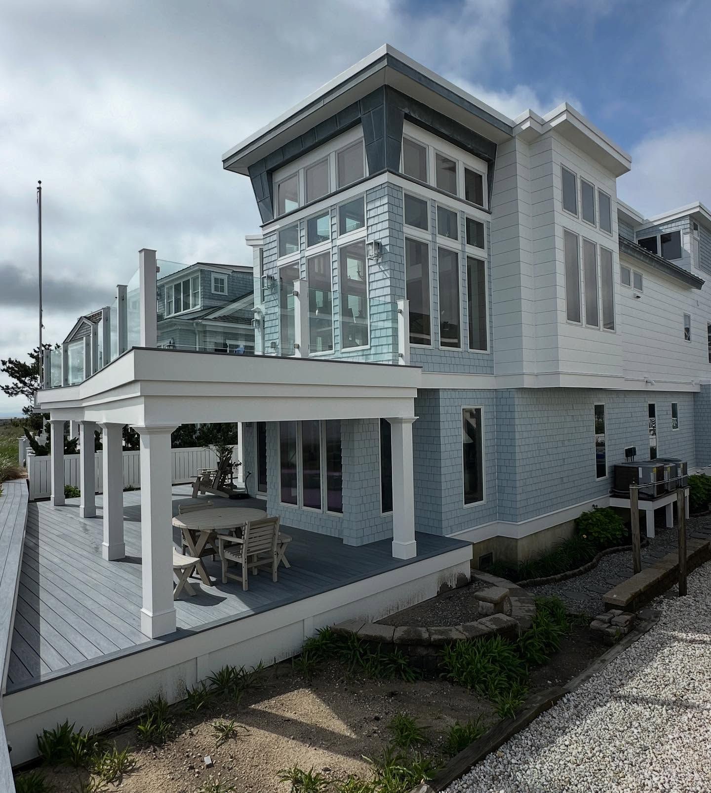 exterior remodel of a modern beach house with gray deck and blue exterior, glass railings by j.k. construction llc in avalon, new jersey