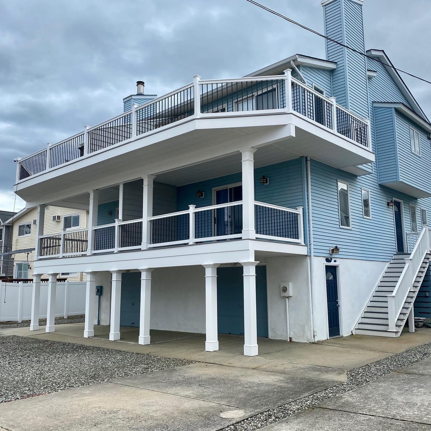 exterior renovation of a two-story blue beach house with white railing, elevated on columns in avalon, new jersey renovated by j.k. construction llc