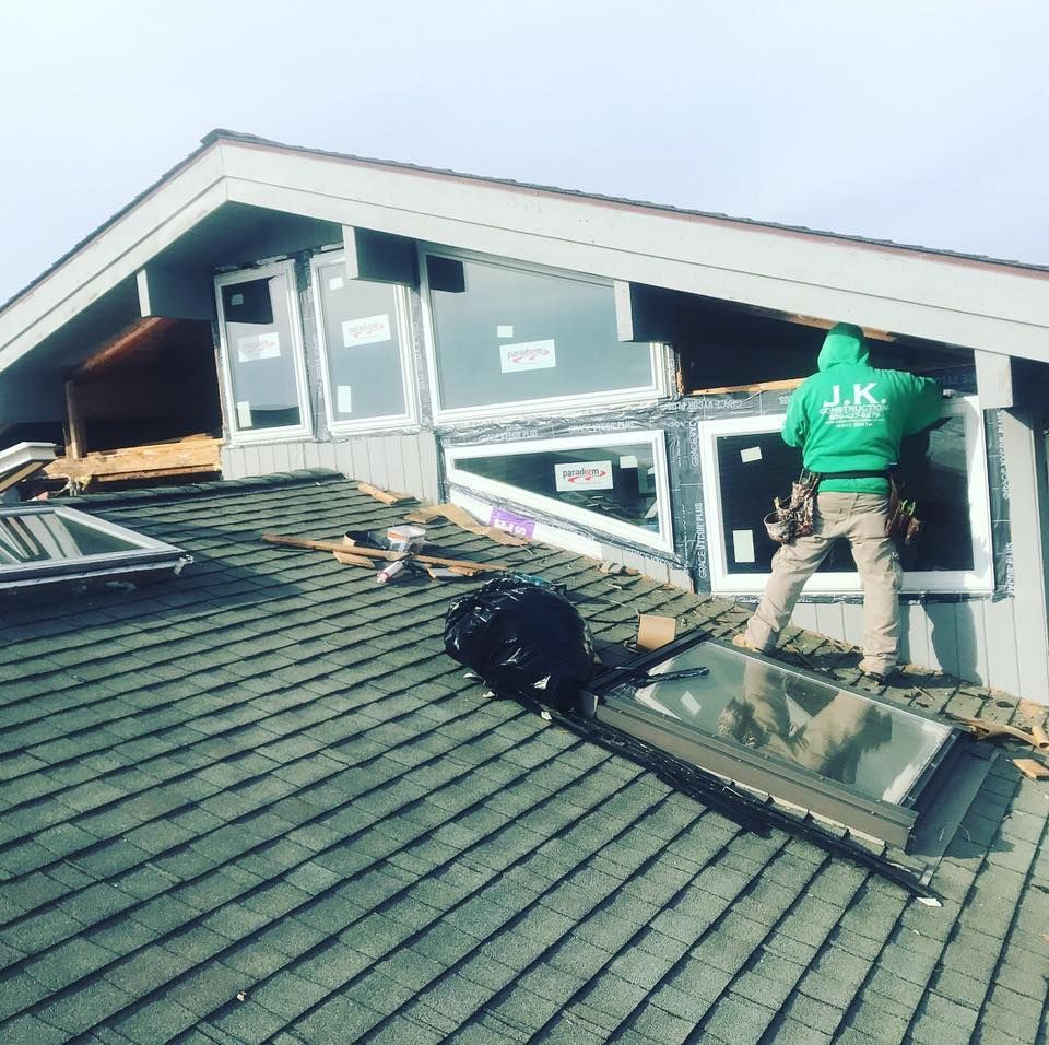 a j.k. construction llc employee in green hoodie installing windows on a house roof in ocean city, new jersey