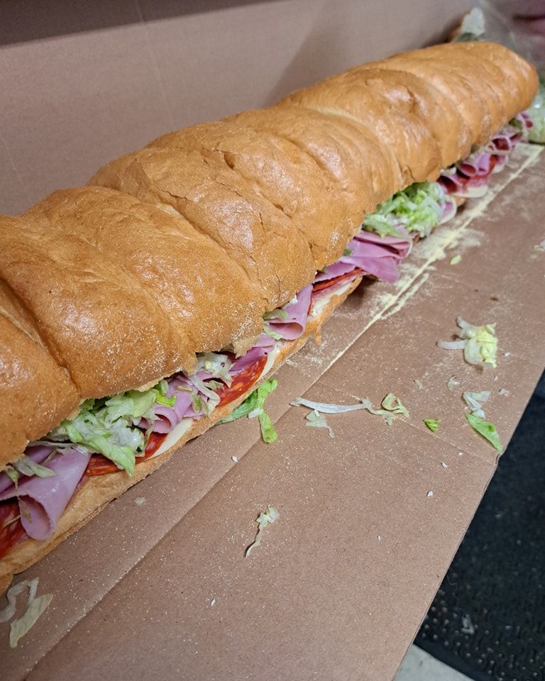 A very long sub sandwich is sitting on top of a cardboard box.