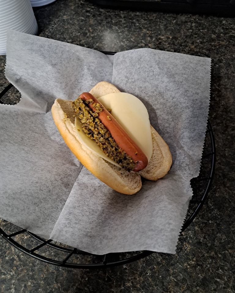 A hot dog with lettuce and cheese on a bun in a basket.