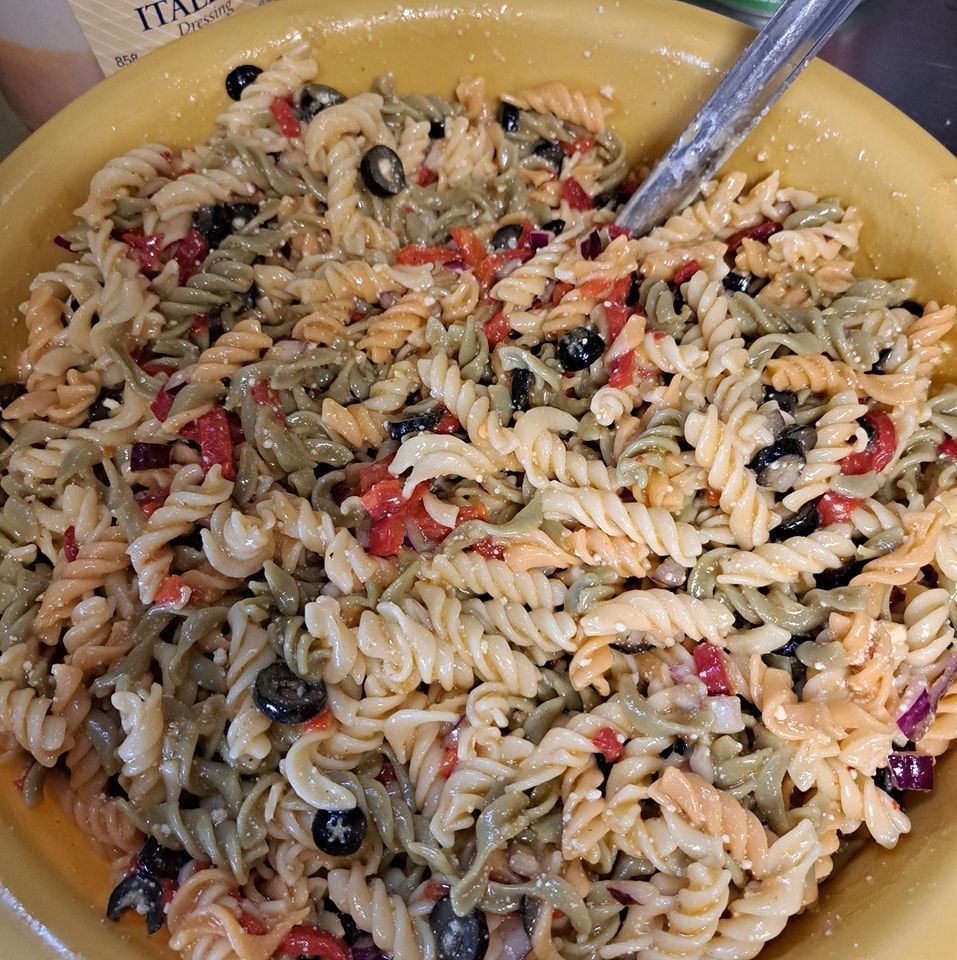 A bowl of pasta salad with a spoon in it