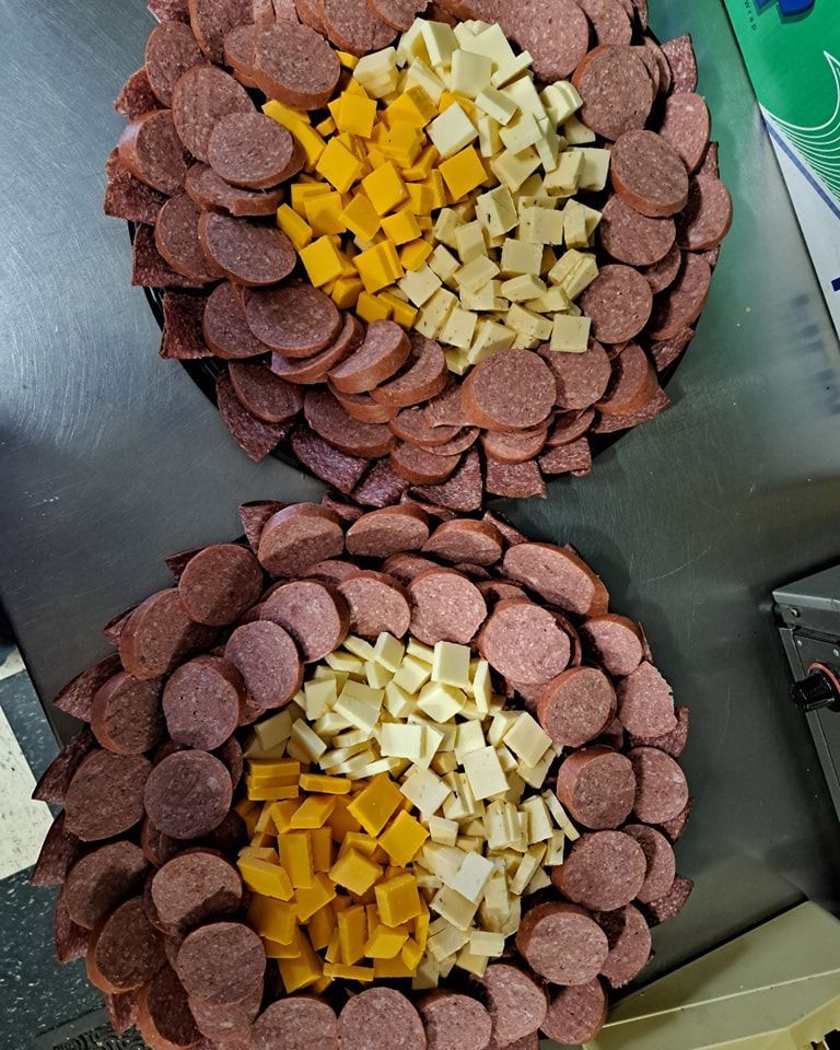 Two trays of sausage and cheese on a table