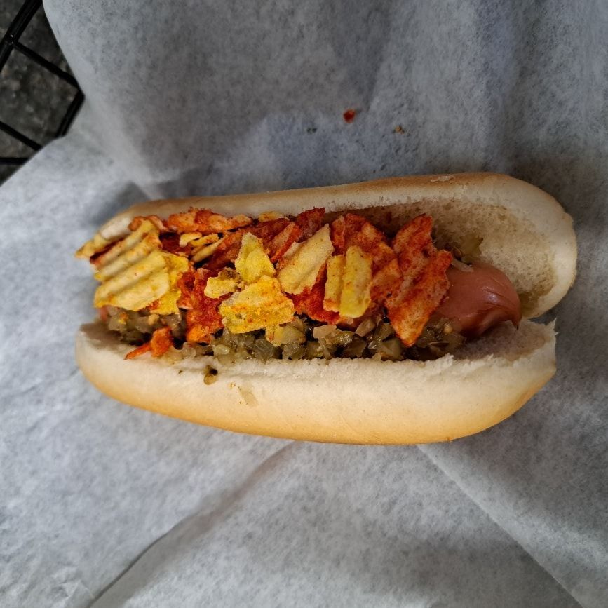 A hot dog on a bun with potato chips on top