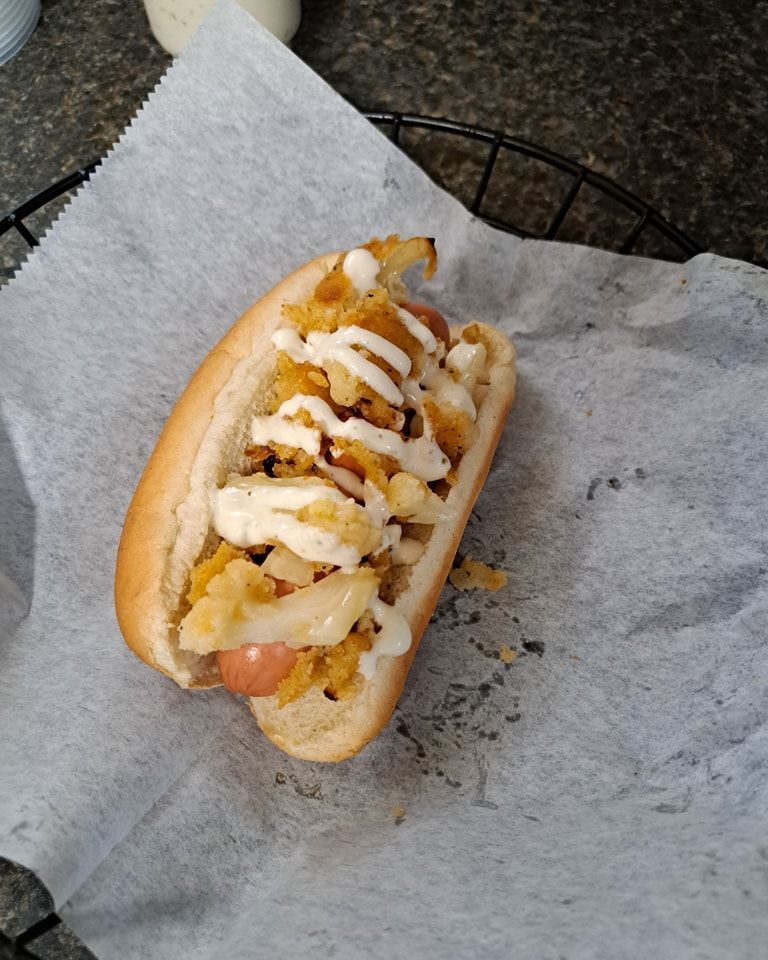 A hot dog with onions and mayonnaise on a bun