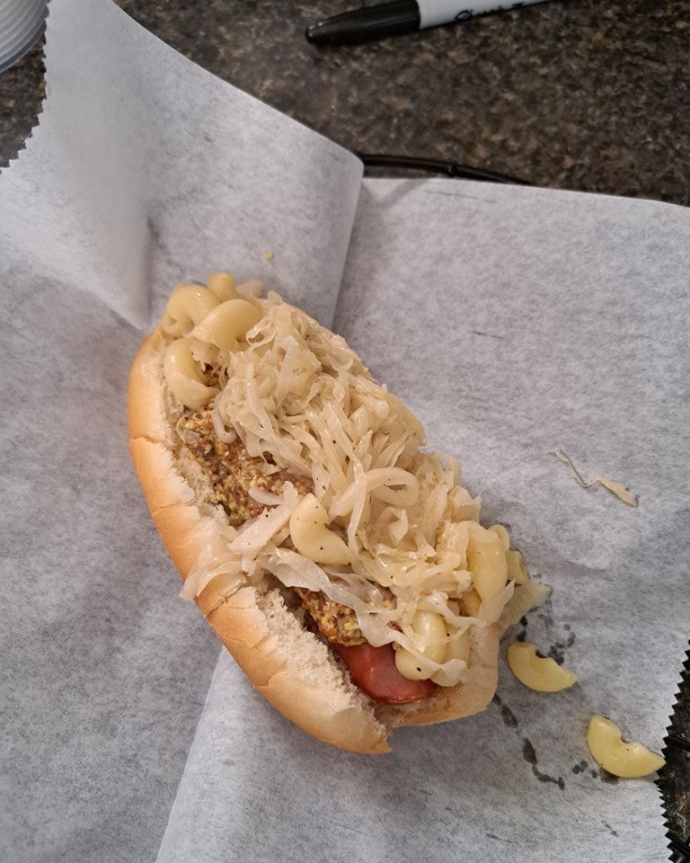 A hot dog with macaroni and cheese on a bun